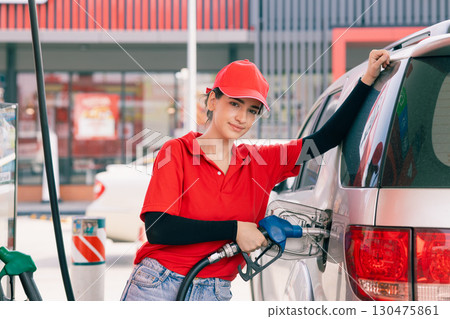 Happy gas station staff worker latin women handle fuel nozzle for refill car fuel 130475861