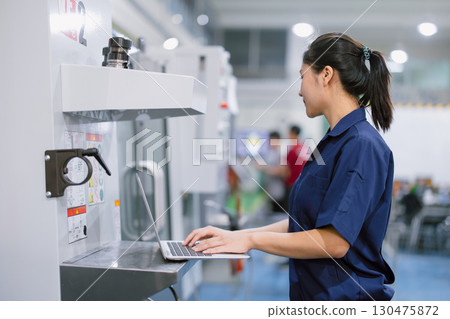 young technician engineer worker with CNC lathe metal machine in modern steel industry factory 130475872