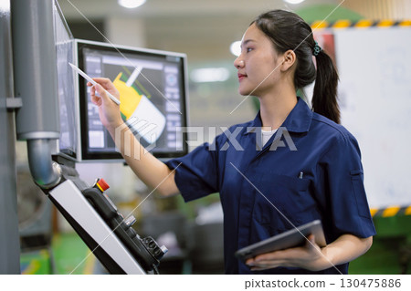 young technician engineer worker with CNC lathe metal machine in modern steel industry factory 130475886