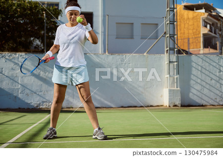 Woman Practicing Tennis on Outdoor Court in Bright Sunny Weather Woman Practicing Tennis on Outdoor Court in Bright Sunny Weather 130475984