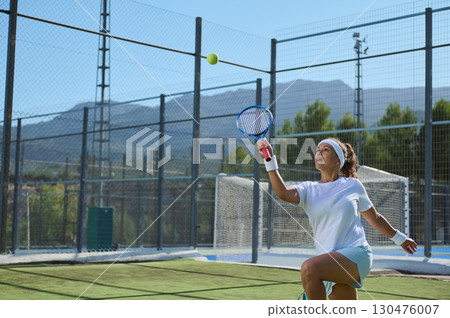Woman Playing Tennis Outdoors on a Sunny Day with Scenic Mountain View 130476007