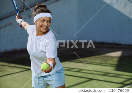 Woman Playing Tennis Outdoors on a Sunny Day in Sporty Attire Woman Playing Tennis Outdoors on a Sunny Day in Sporty Attire 130476009