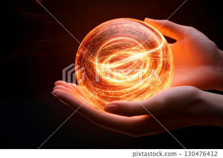 Hands hold a glowing sphere of swirling energy, representing light and power in an enchanting close-up moment 130476412
