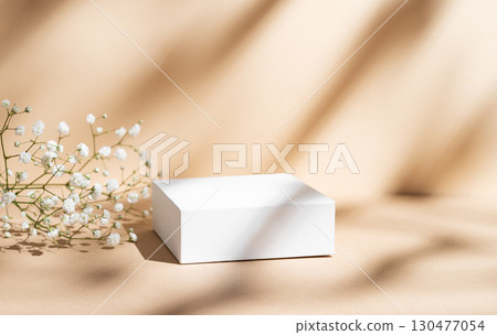 White square box on a beige background with gypsophila flowers and soft shadows. 130477054