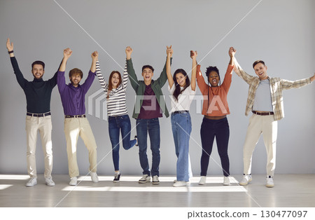 Group of a happy people coworkers or friends looking at camera, holding hands up and smiling. Group of a happy people coworkers or friends looking at camera, holding hands up and smiling. 130477097