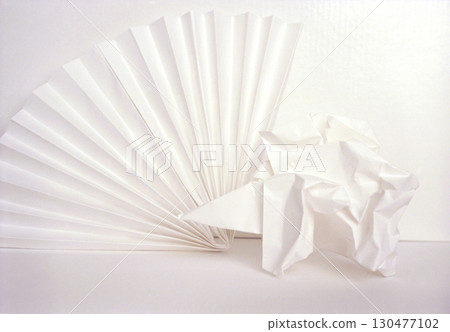Artwork featuring white paper fan and crumpled paper on blank background showcasing texture and simplicity 130477102