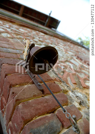 Vintage bell mounted on a rustic brick wall, showcasing classic architecture in a serene outdoor setting Vintage bell mounted on a rustic brick wall, showcasing classic architecture in a serene outdoor setting 130477112