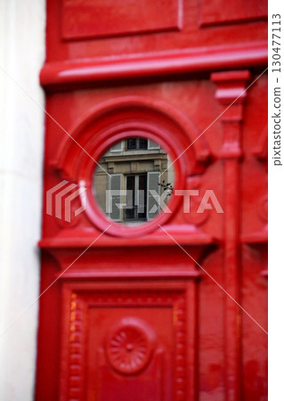 Red door with circular window reflecting elegant architecture in a city street Red door with circular window reflecting elegant architecture in a city street 130477113