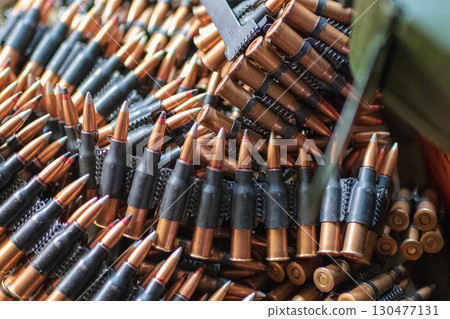 Collection of ammunition cartridges assembled for military use in an outdoor setting during the daytime Collection of ammunition cartridges assembled for military use in an outdoor setting during the daytime 130477131