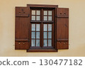Wooden window with shutters and grid design on a beige wall in a historic building 130477182