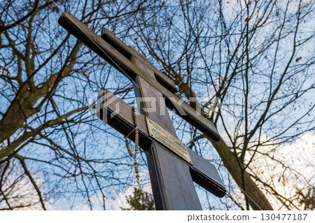 Cross surrounded by bare trees under a clear sky during sunset near a historical site 130477187