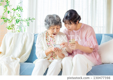 Senior woman playing with her grandchild on a smartphone 130477398