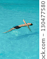 Boy floating relaxed in a swimming pool. 130477580
