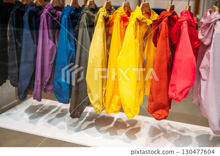 Colorful array of windbreakers in a full spectrum palette hanging neatly in a boutique display. Slow fashion, mindful wardrobes, sustainable shopping habits, eco-conscious dressing Colorful array of windbreakers in a full spectrum palette hanging neatly in a boutique display. Slow fashion, mindful wardrobes, sustainable shopping habits, eco-conscious dressing 130477604