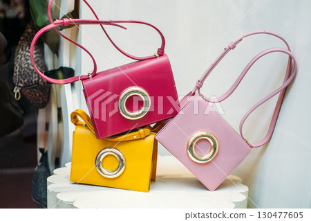 Colorful handbags with oversized metallic rings on display in a boutique window. Dopamine dressing accessories, playful fashion, statement design, mood-boosting style Colorful handbags with oversized metallic rings on display in a boutique window. Dopamine dressing accessories, playful fashion, statement design, mood-boosting style 130477605