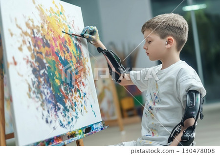 Creative artist with prosthetic arms passionately expresses himself through painting in an art studio space during daytime 130478008