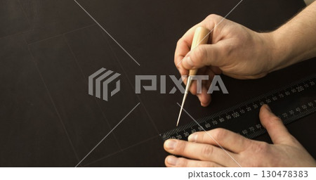 Artisan using awl and ruler to draw precise lines on leather surface for handmade accessory making Artisan using awl and ruler to draw precise lines on leather surface for handmade accessory making 130478383