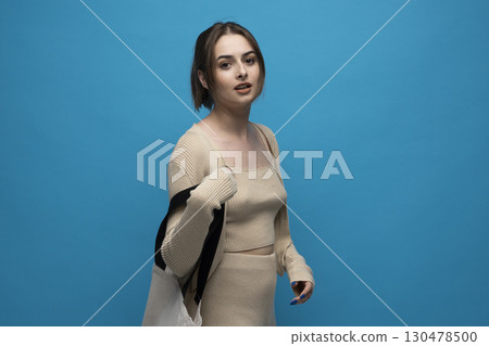 Stylish young woman wearing beige outfit posing with eco-friendly tote bag Stylish young woman wearing beige outfit posing with eco-friendly tote bag 130478500