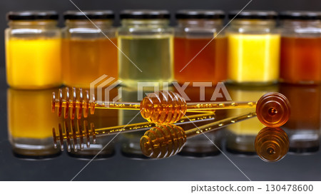 Honey jars and dipper displayed in an artistic arrangement on a reflective surface Honey jars and dipper displayed in an artistic arrangement on a reflective surface 130478600