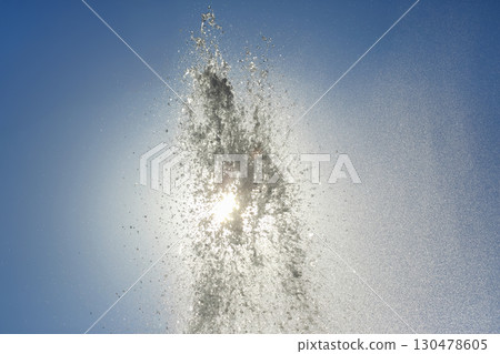 Water fountain sprays sunlight into a clear blue sky during a bright afternoon Water fountain sprays sunlight into a clear blue sky during a bright afternoon 130478605