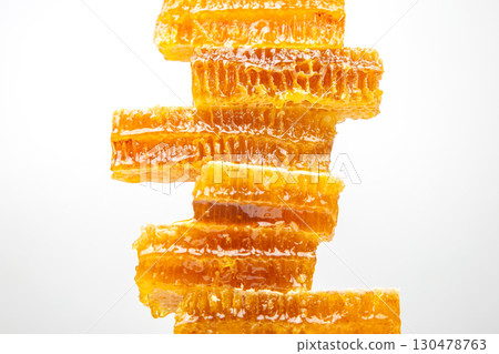 Honeycomb pieces stacked vertically showing golden honey glistening under bright light Honeycomb pieces stacked vertically showing golden honey glistening under bright light 130478763