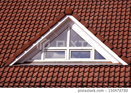 Unique architectural window design featuring a triangular shape on a tiled roof 130478780