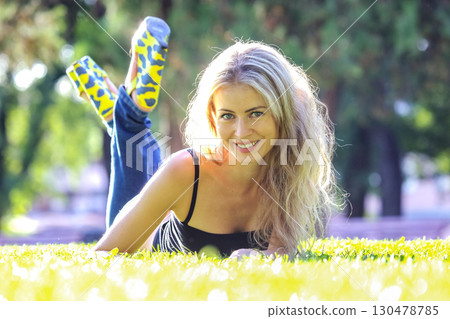 Young woman relaxing on grass in a park during a sunny afternoon 130478785