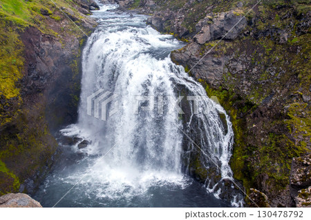 Majestic waterfall cascading into river surrounded by lush green moss in Iceland Majestic waterfall cascading into river surrounded by lush green moss in Iceland 130478792