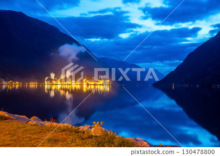 Industrial lights reflect on calm waters in a Norwegian fjord at twilight 130478800