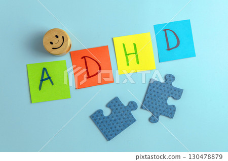 ADHD abbreviation on multi-colored paper and puzzle pieces with the smiley. Attention Deficit Hyperactivity Disorder concept 130478879