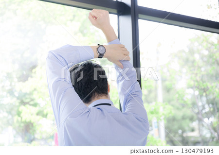 Businessman taking a break and stretching by the window, back view without face Businessman taking a break and stretching by the window, back view without face 130479193