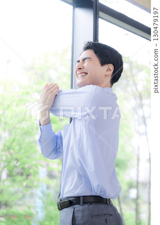 Businessman taking a break stretching by the window Businessman taking a break stretching by the window 130479197
