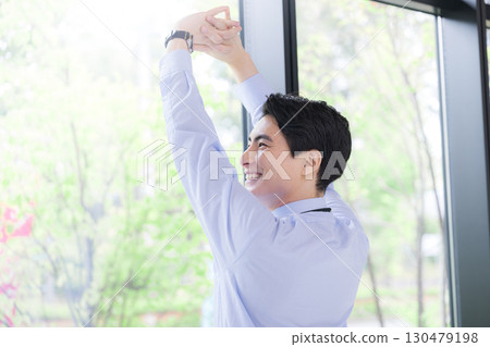 Businessman taking a break stretching by the window Businessman taking a break stretching by the window 130479198