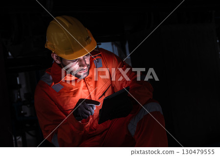 Engineer man technician male working at night shift with tablet technology device on site service 130479555