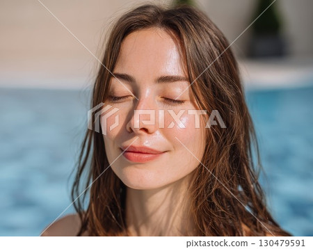 Young woman with freckles enjoys sunny day by pool, showcasing natural beauty and serene mood. Perfect for beauty and summer themes. 130479591