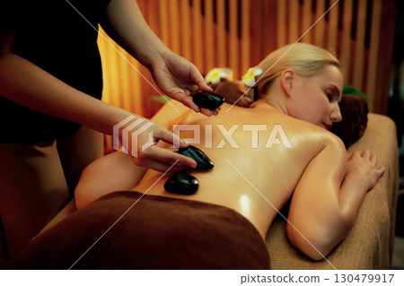 Hot stone massage at spa salon in luxury resort with warm candle light.Quiescent 130479917