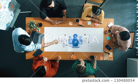Diverse Team Collaborating Over Conference Table with Charts and Tablet in Modern Office Setting for Business Development Strategy. Raster 130480054