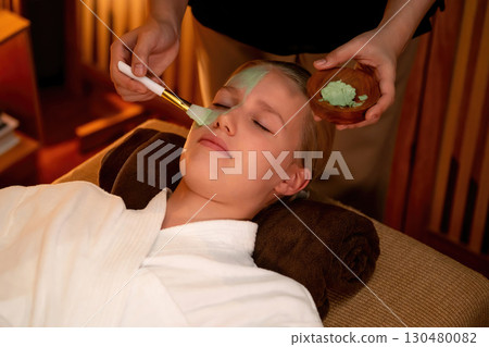 Woman indulges in rejuvenating with luxurious face cream spa massage. Quiescent 130480082