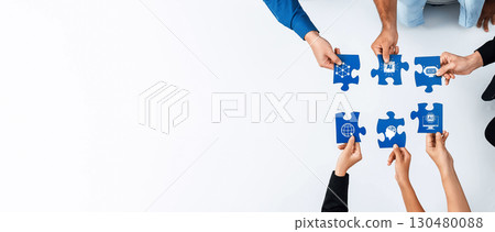 Collaborative teamwork concept featuring hands holding puzzle pieces with diverse icons representing global cooperation and problem-solving in a modern workspace. Amity Collaborative teamwork concept featuring hands holding puzzle pieces with diverse icons representing global cooperation and problem-solving in a modern workspace. Amity 130480088