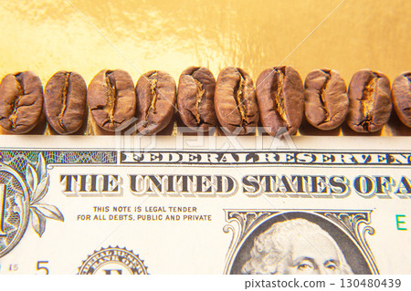 Roasted coffee beans aligned on a U.S. dollar bill, highlighting currency details 130480439