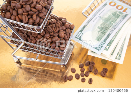 small shopping cart filled with roasted coffee beans sits on a golden surface 130480466