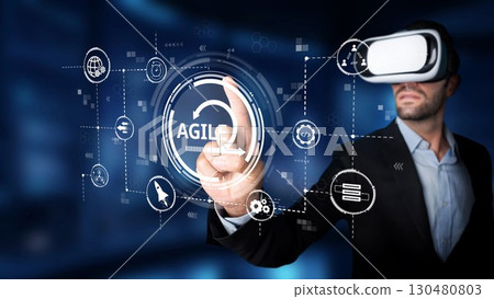 Businessman in Virtual Reality Glasses Exploring Innovative Agile Technology Concepts in Futuristic Digital Environment with Graphical User Interface Elements. Raster 130480803