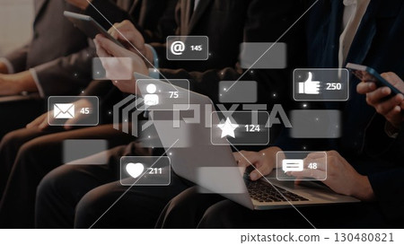 Group of Business People Engaging with Technology Displays Social Media Icons and Notifications on Mobile Devices and Laptop in Modern Office Environment. Raster Group of Business People Engaging with Technology Displays Social Media Icons and Notifications on Mobile Devices and Laptop in Modern Office Environment. Raster 130480821