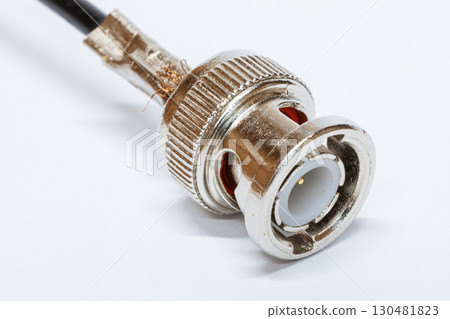 Macro photo of BNC connector on white background. Metal connector with central contact used for coaxial cables in video communication and radio equipment. BNC connector crimping. 130481823