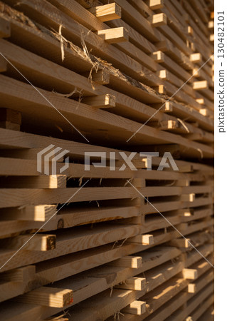 Wooden boards stacked at lumberyard in sunlight 130482101
