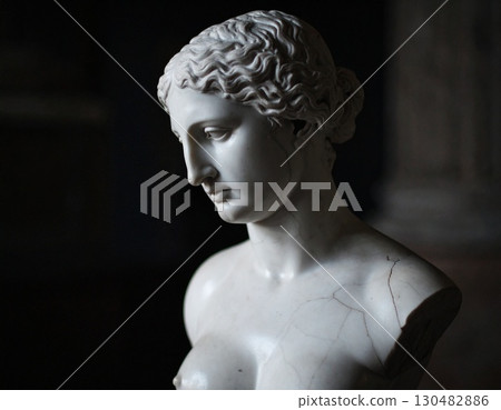 A cracked statue's delicate face evokes a sense of history and fragility 130482886