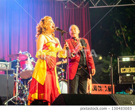 Elderly colorful fashionable couple embraced happily smiling sing in front of music stage 130483083