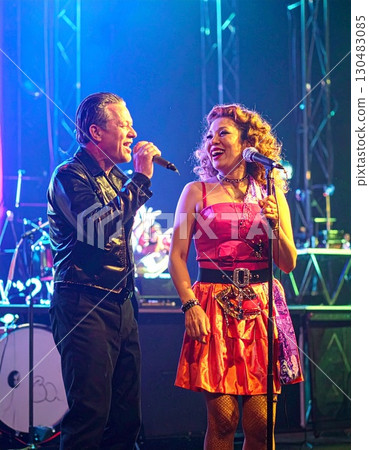 Elderly colorful fashionable couple embraced happily smiling sing in front of music stage 130483085
