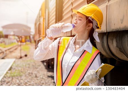 Young lady engineer worker drinking water refresh when working outdoor hot sunny day in summer Young lady engineer worker drinking water refresh when working outdoor hot sunny day in summer 130483404