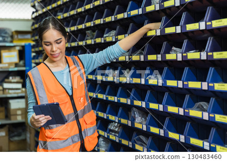 Happy woman worker engineer technician staff work in factory products inventory parts storage room Happy woman worker engineer technician staff work in factory products inventory parts storage room 130483460